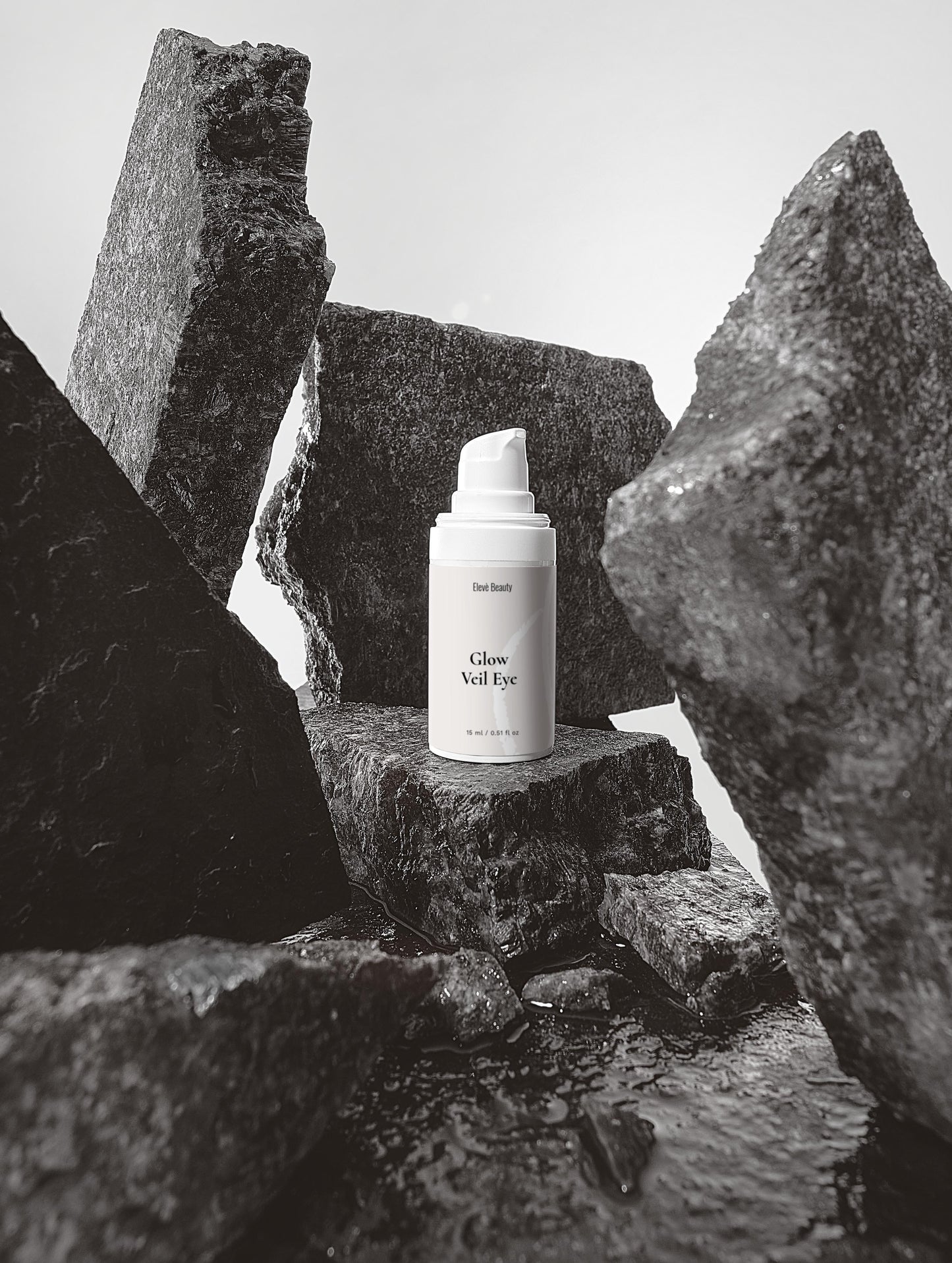 Glow Veil Eye Serum mitten von dekorativen dunklen Steinen. Man sieht die Vorderseite der Flasche.