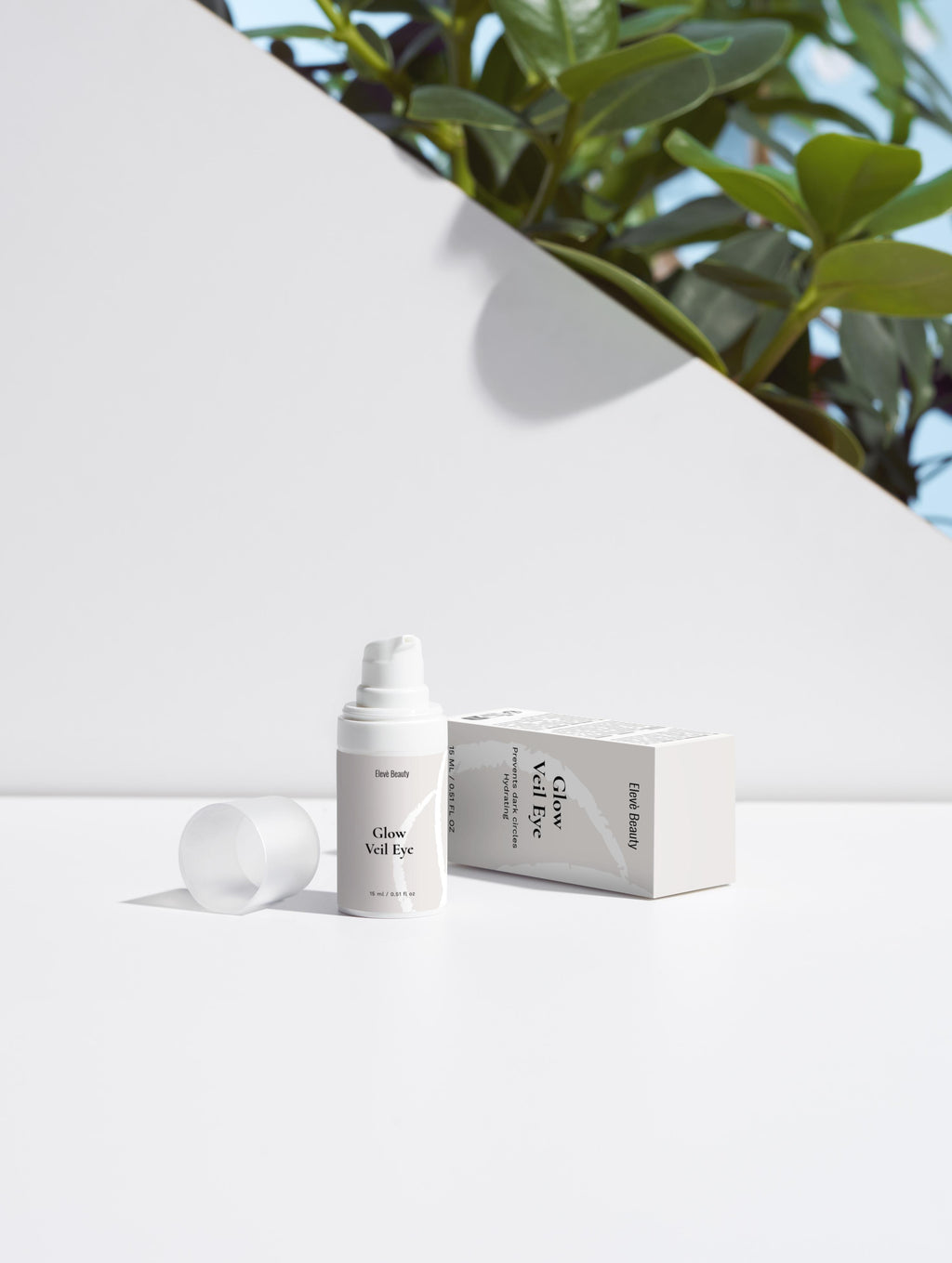 Glow Veil Eye Serum mit Flasche und Verpackung auf einem neutralen weißen Hintergrund. Im Hintergrund sind gründe Blätter.