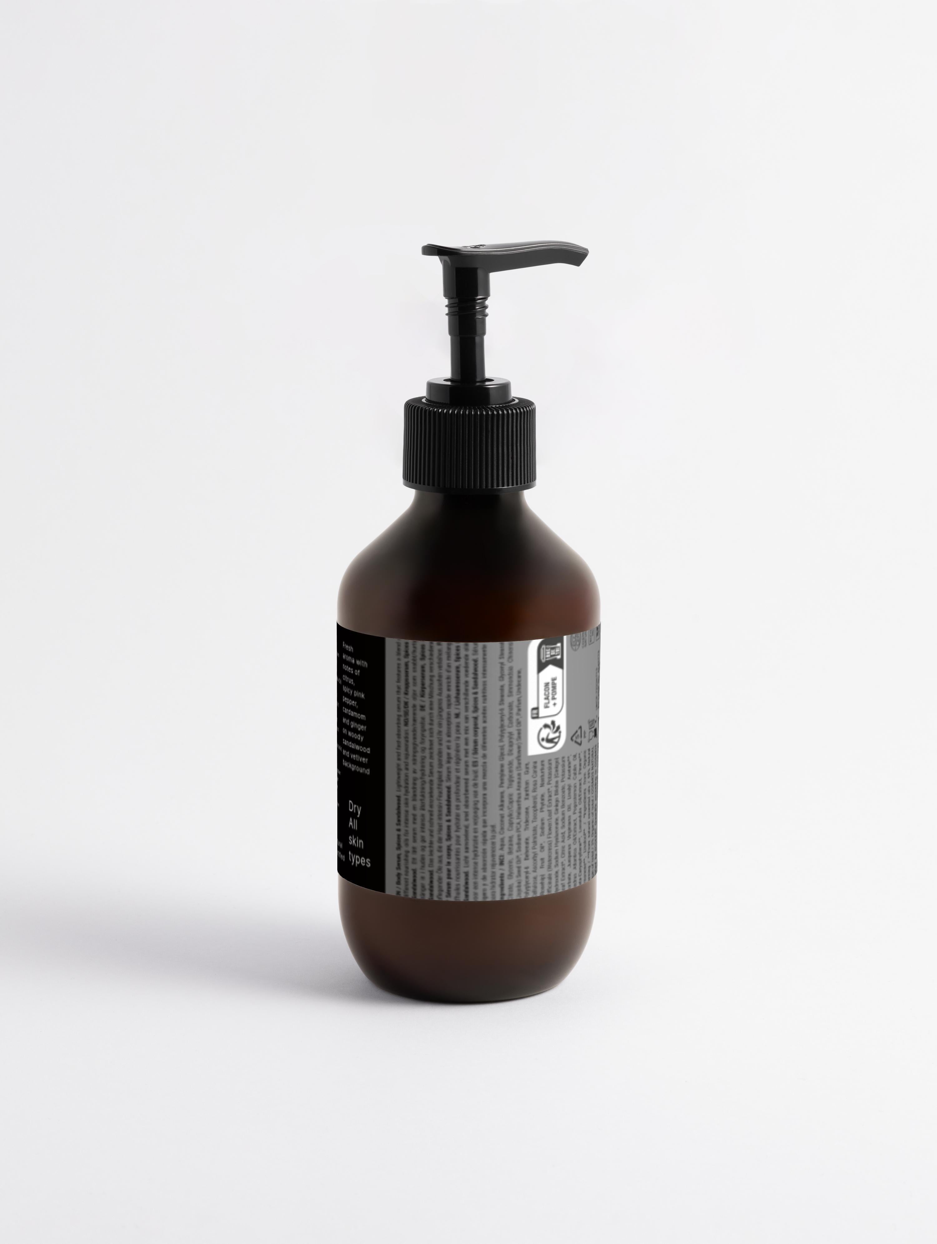Rückseite der Elevè Body Lotion in einer transparenten, braunen Pumpflasche auf weißem Hintergrund -mit Inhaltsstoffangaben und eleganten Etikettendesign. 