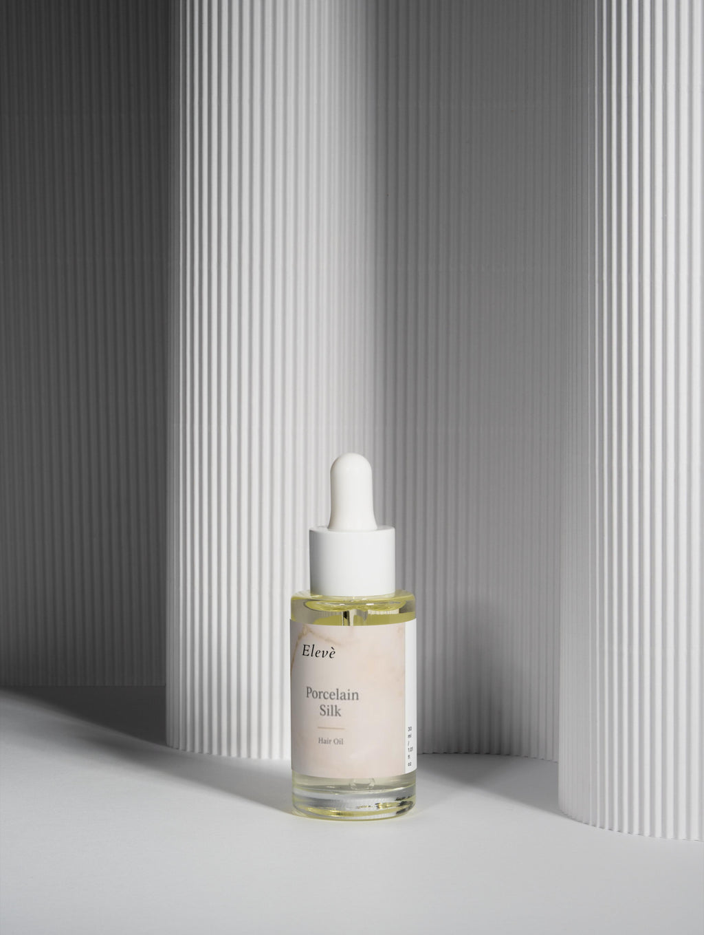 Minimalistisches Elevè Haaröl im Glasflakon mit Pipette auf hellem Hintergrund für glänzendes und gepflegtes Haar