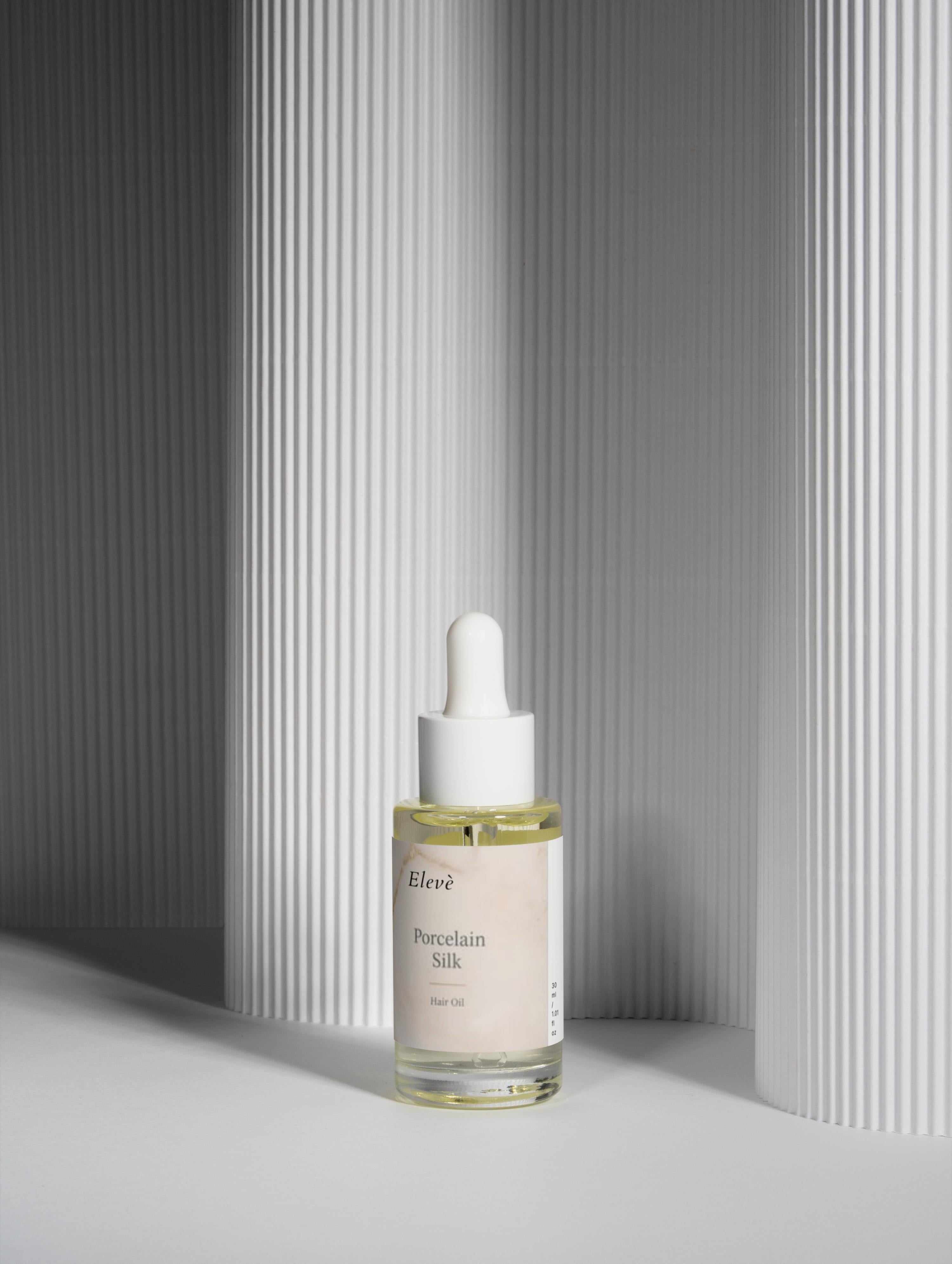 Minimalistisches Elevè Haaröl im Glasflakon mit Pipette auf hellem Hintergrund für glänzendes und gepflegtes Haar